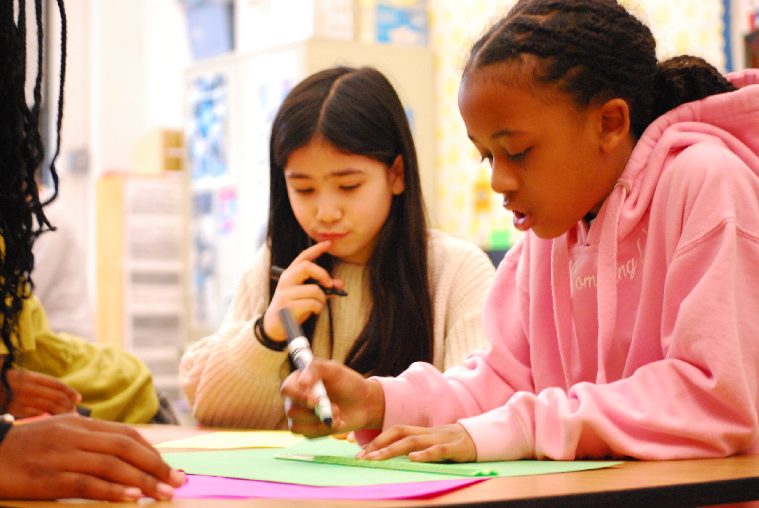 Two students look deep in thought as they work together on a project in their classroom.