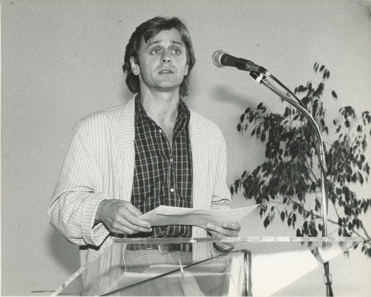 A black and white photo of Mikhail Baryshnikov speaking into a microphone.
