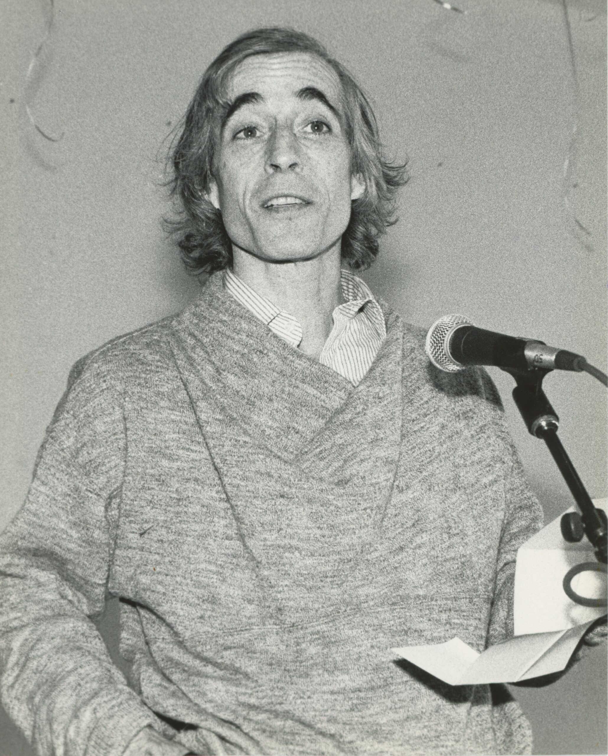 A black and white photo of Eliot Feld speaking into a microphone.