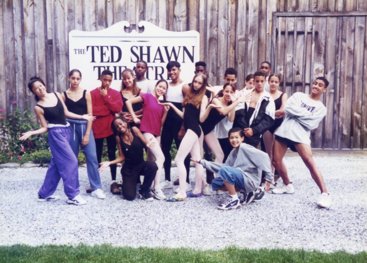 Students in dancewear and warmups pose together outside of the Ted Shawn Theater at Jacobs Pillow.